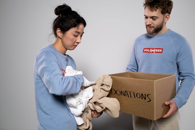 The couple packs items intended for donations in a cardboard box.