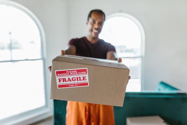A man holds out a cardboard box labeled fragile