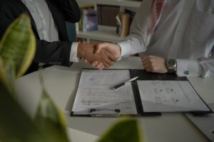 Two people shaking hands after reviewing the legal aspects of buying and selling a home.
